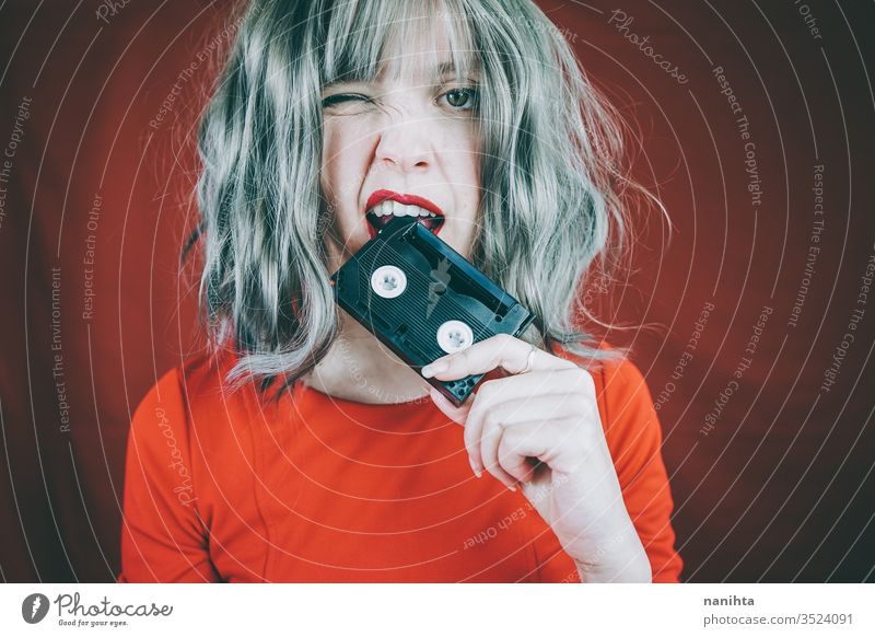 Artistic portrait with a model covering her face with a retro video tape vintage cassette red woman sexy pretty music culture 90s 80s decade old concept idea