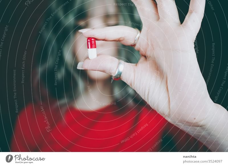 Young woman's hand holding a white and red pill drug medicine virus addict addictive addiction painkiller pain killers close up bokeh closeup blur focus macro