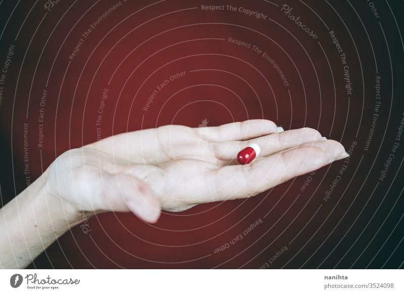 Young woman's hand holding a white and red pill drug medicine virus addict addictive addiction painkiller pain killers close up bokeh closeup blur focus macro