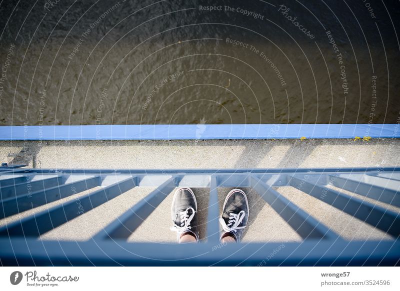 There I stand on a bridge at the railing and look at my feet and at the river Elbe in the depth pile-lander Stand stopped foot depth effect look down River