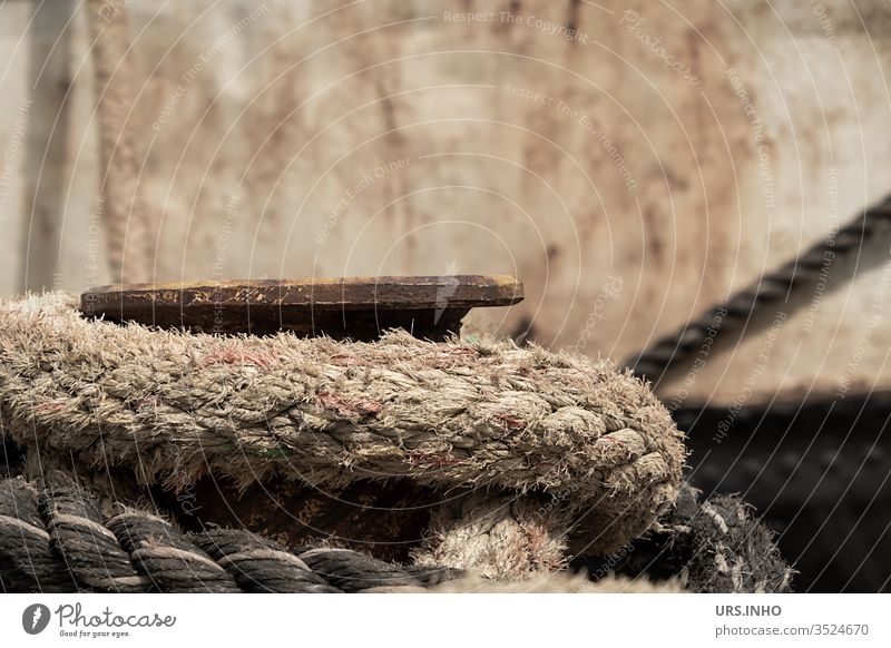 Harbour bollard wrapped with mooring line in front of a hull Dew firecracker harbour bollards Wrapped around Hull in the background mooring rope Holding pile