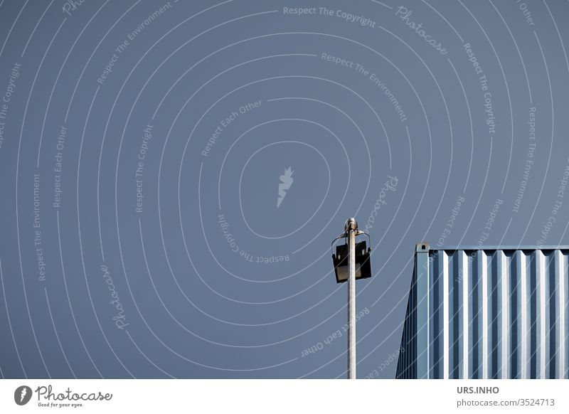 Detail of a storage container and a mast-mounted outside light in front of a cloudless sky Floodlight Container clear Blue detail minimal Minimalistic