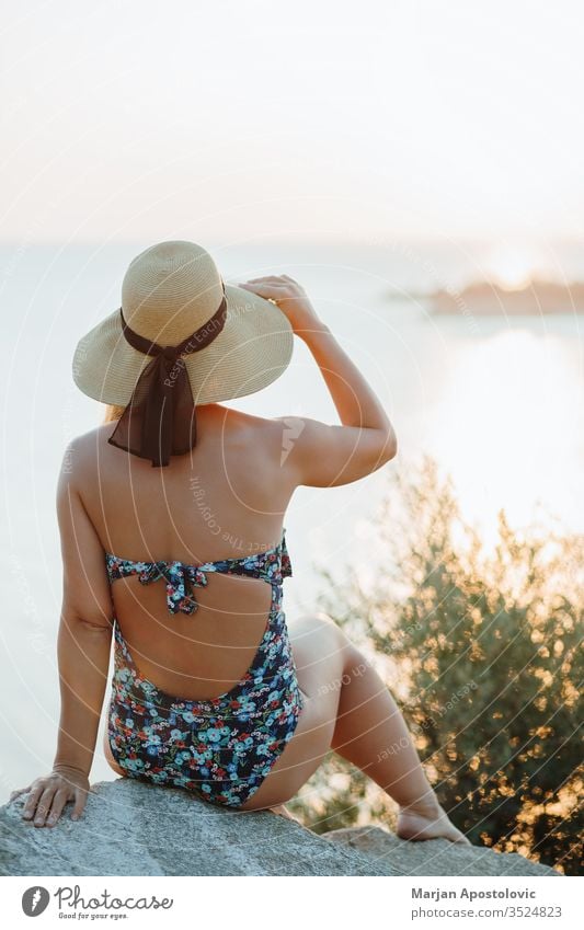 Young woman enjoying sunset by the sea adventure beautiful beauty carefree cliff coast coastal coastline evening female freedom girl hat holiday horizon