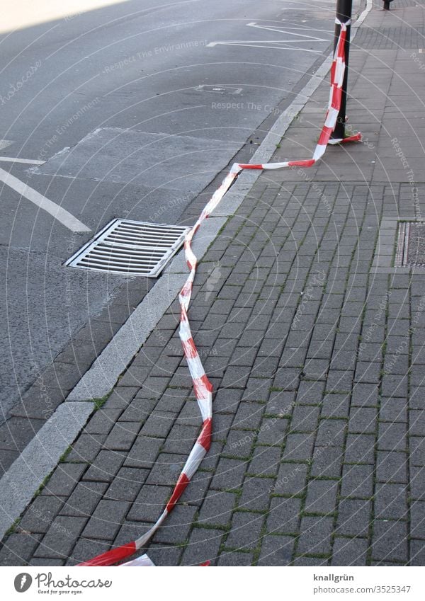 Fluttering tape along the road and the sidewalk lying on the ground flutterband cordon Street Marker line Gully Paving stone Edge of the road Curbstone