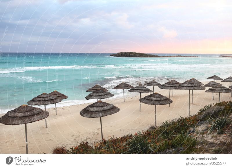 beautiful straw umbrellas on the beach on the empty beach, bright blue water and sky, paradise tropical beach,relaxing time,,amazing view,no people, sunset background. selective focus