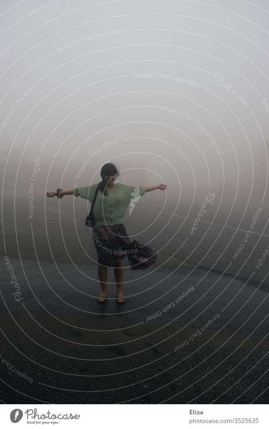 A young woman stands with outstretched arms in the clouds on the cloud pass in Vietnam Woman extended arms Cloud Pass Clouds Fog Gray Wind windy dystopic