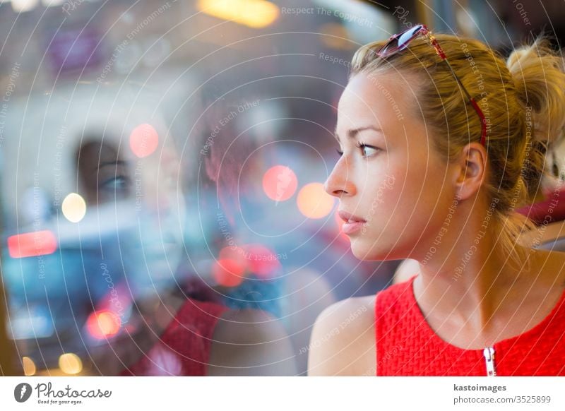 Woman looking out tram's window. transport portrait woman travel bus female urban view observe casual fashion thoughtful modern street style trip sitting