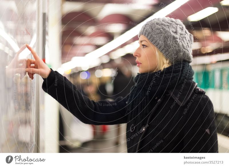 Lady looking on public transport map panel. metro woman station commute urban transportation train line city direction subway search underground travel platform