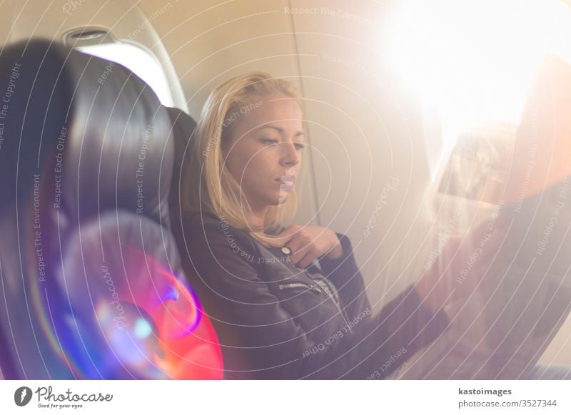 Woman reading newspaper on airplane. passenger woman travel flight transport trip female seat young transportation girl inside journey caucasian cabin window