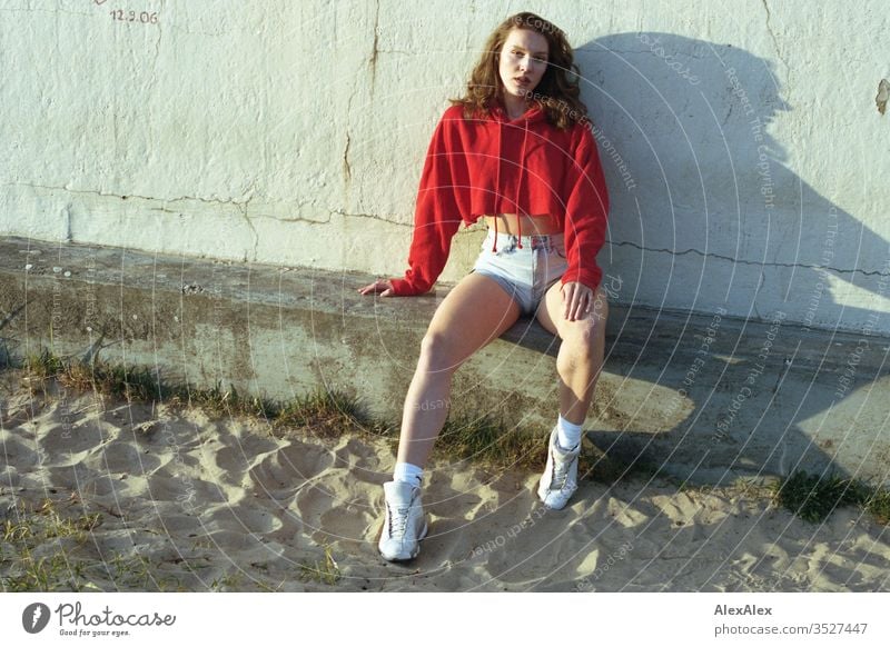 analogue portrait of a young woman with red hoodie and hot pants Woman girl already great Athletic Slim fit brunette Red Hot pants Curl long hair sneakers Legs