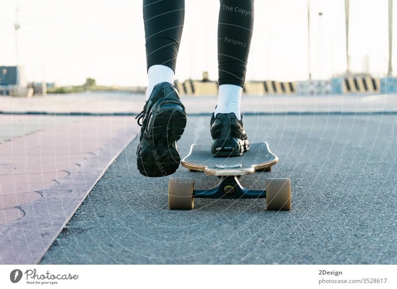 Unrecognizable woman rides on longboard around sunlit park. close up enjoy futuristic legs owner path rider scenery shadow sports sunshine trail transportation