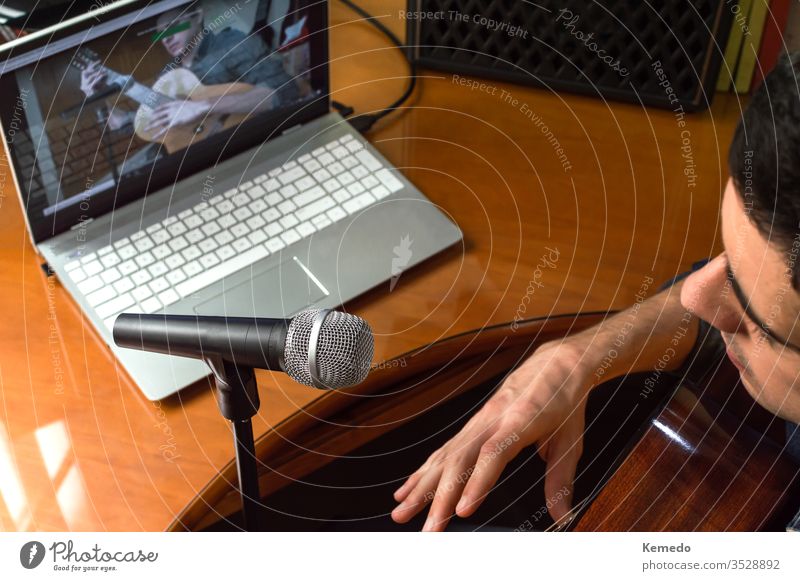 Young man recording himself while playing guitar and singing to share the video in social media. Musician recording a music video at home. musician influencer