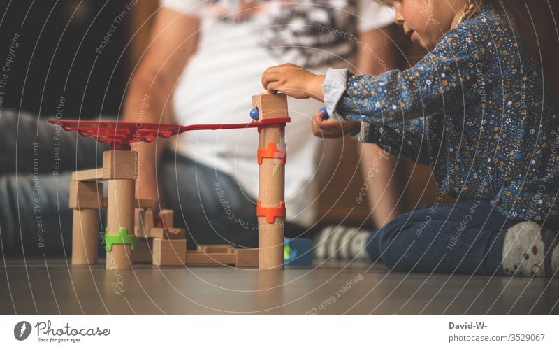 Child plays with wooden toys Toys Playing Children's room Father Sit Crouch inside Marbles Build creatively fun Joy cheerful concentrated cautious Emotionally