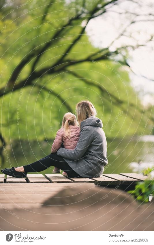 Mother sits with child on a jetty on the shore of a lake Child girl Nature natural Family Parents Infancy Cute Love Safety (feeling of) tranquillity