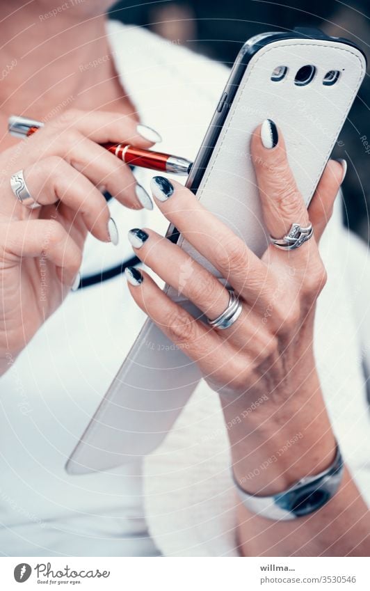 Woman with pen and smartphone in her hand and beautifully styled fingernails stylus Touchpen hands manicured Smartphone pen Stylus Digital mobility Inform SMS