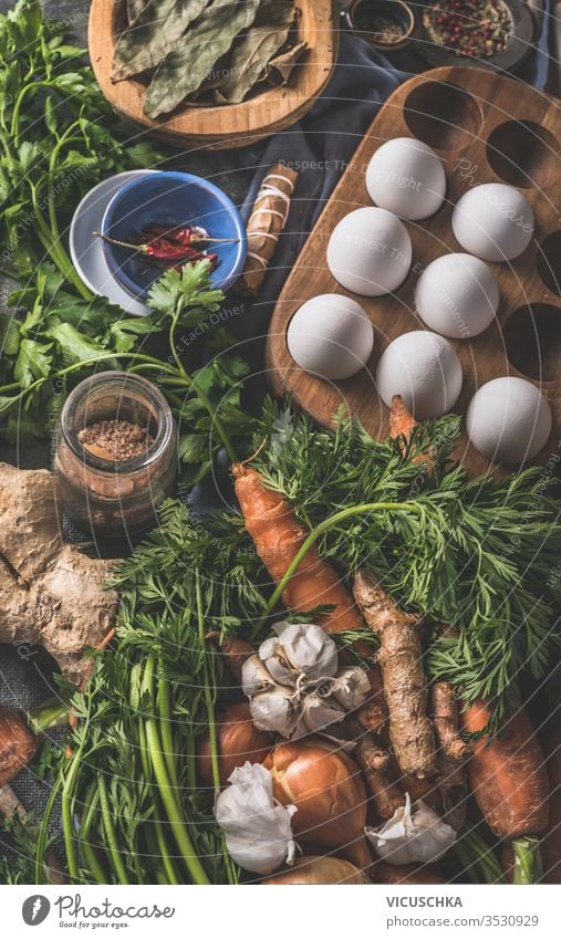 Various ingredients for tasty paleo diet. Healthy natural organic food concept. Carrots, onions, eggs, ginger roots vegetables, seasonings on dark rustic kitchen table background , top view.