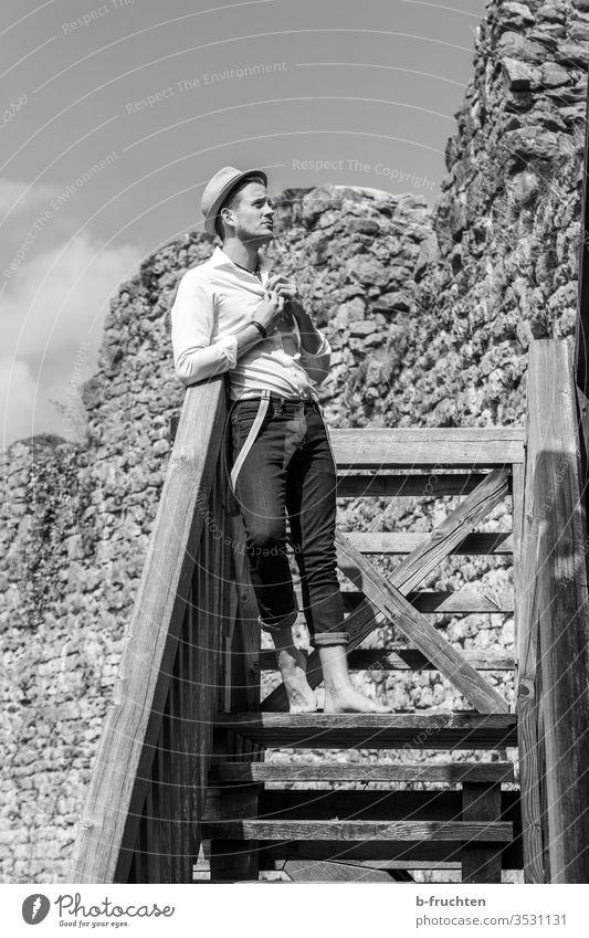 Young man on a wooden staircase in an old ruin Man look Black & white photo Ruin Hat Human being Adults portrait Shirt Barefoot Stairs wooden rail Old Future