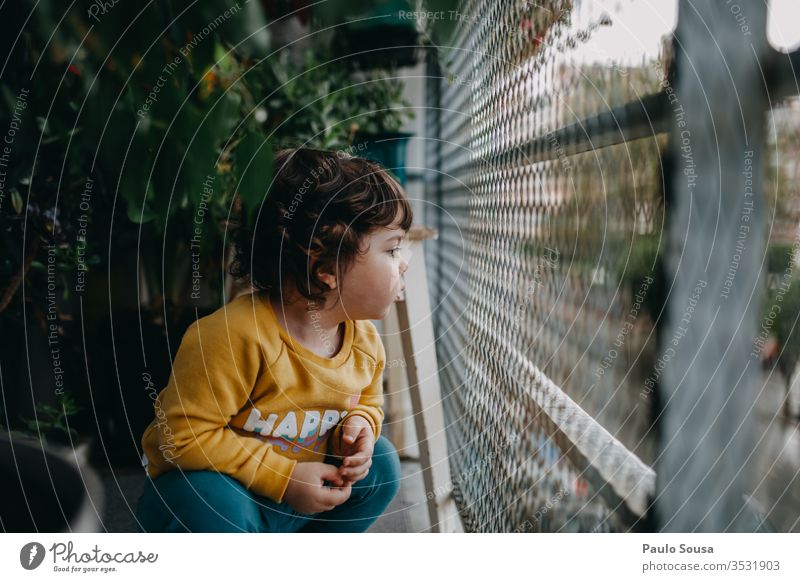 Child in the balcony childhood at home Lifestyle Autumn Authentic fall Balcony balcony rail Balcony planting green lockdown Green stay at home Exterior shot