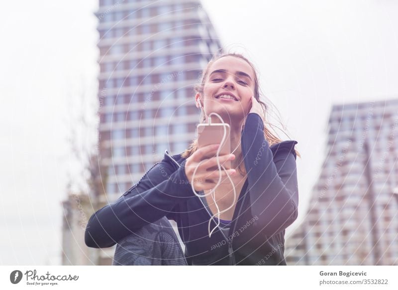 Smiling young woman with smartphone and headphones listening to music lifestyle female happy girl outdoor modern person summer teenager earphones outside