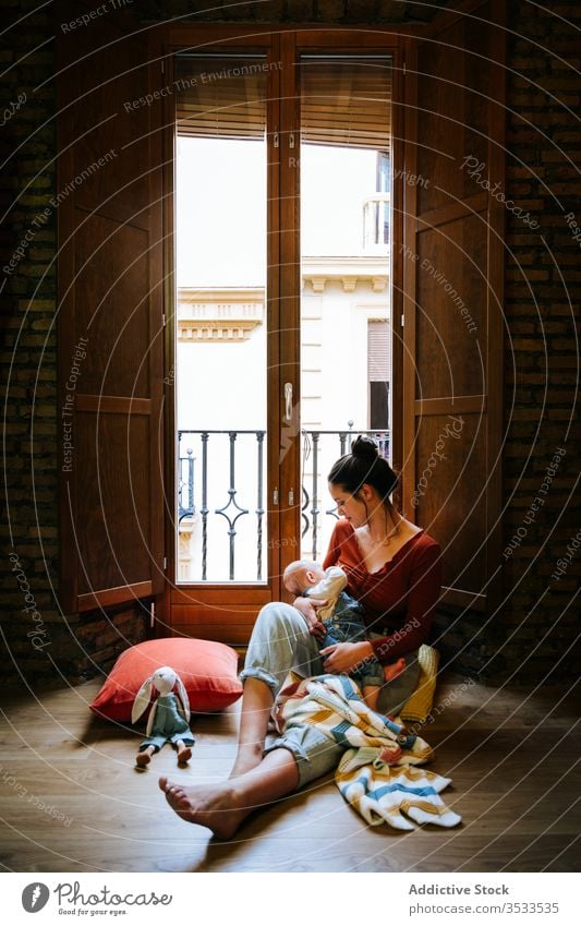 Happy mother breastfeeding baby near window home happy love rest cozy sit woman cute room hug embrace smile child kid childhood little care together parent