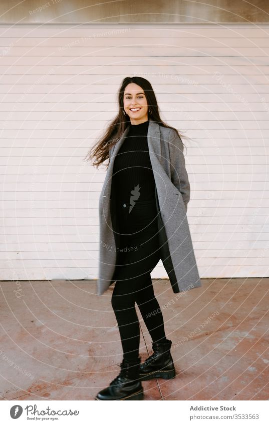 Happy young woman spinning around on street city smile urban style fun dance female excited coat trendy building wall fashion happy amazed model lady cheerful