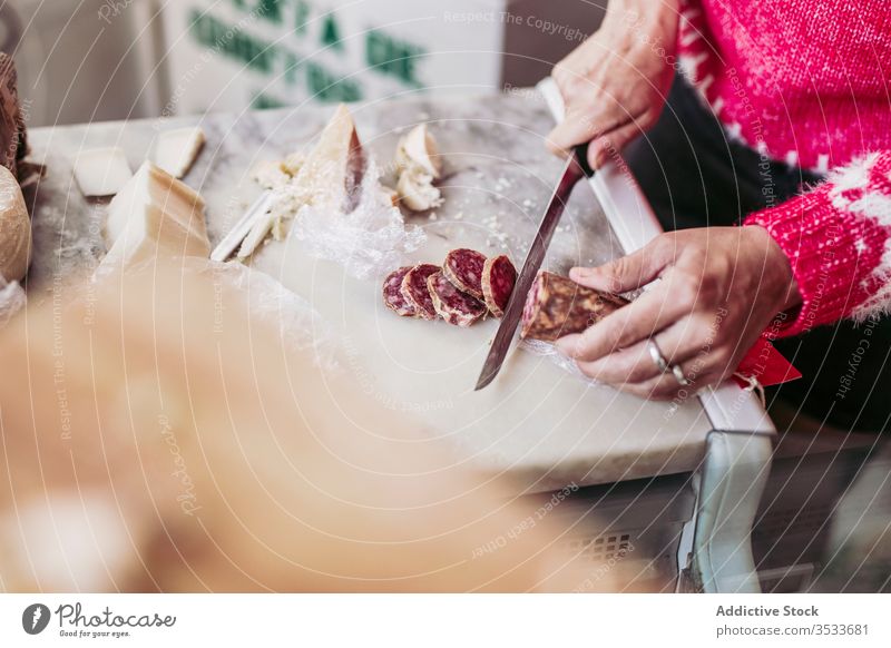 Crop seller cutting sausage on counter shop food local cuisine work knife cheese meal yummy market tasty product tradition gourmet delicious fresh store grocery