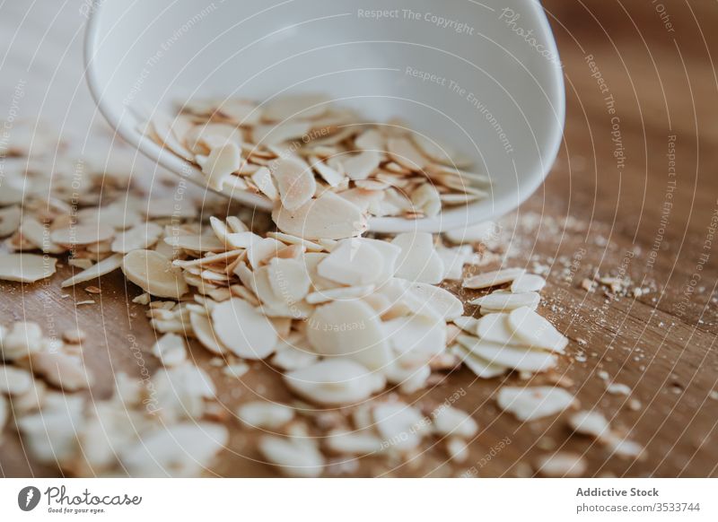 Bowl of healthy almond chips spilled on wooden table bowl ingredient vegan ripe kitchen food nut dessert home seed morning sweet snack fresh vegetarian heap