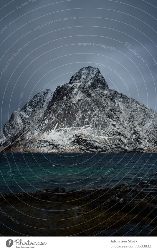 Amazing landscape of snowy rocks on sea coast in cloudy winter day ridge mountain water overcast sky idyllic lofoten adventure shore tourism altitude norway