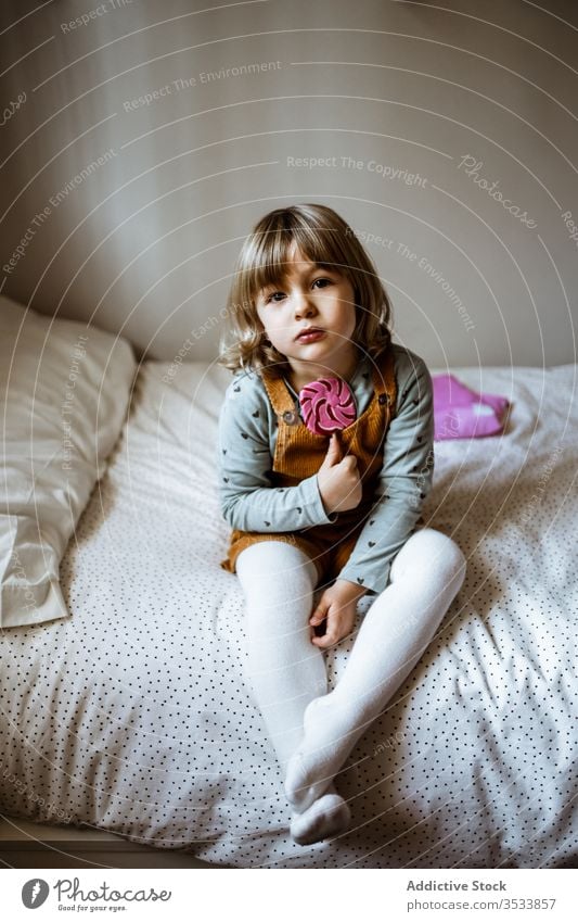 Little girl eating candy on bed lollipop suck home toy sit rest cute little bedroom child kid plush sweet childhood soft cozy innocent relax casual lifestyle