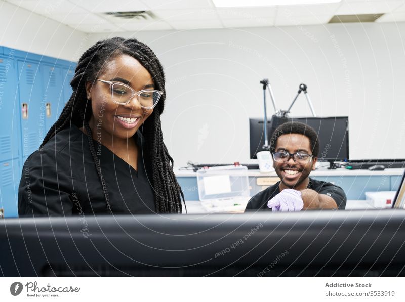 Ethnic colleagues examining data on lab computer laboratory discuss ethnic together work smart modern man women uniform contemporary research coworker