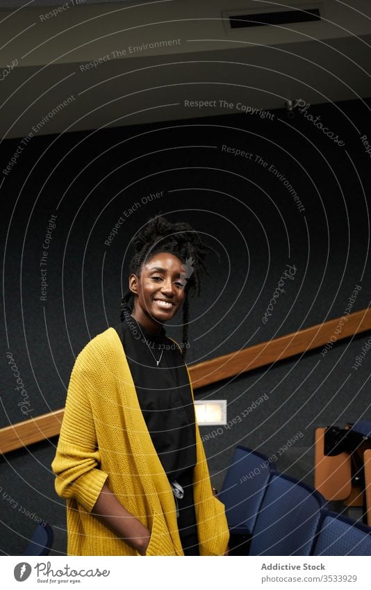 Black student looking at camera in auditorium woman ethnic study modern university lecture female hall classroom casual education black african american lady