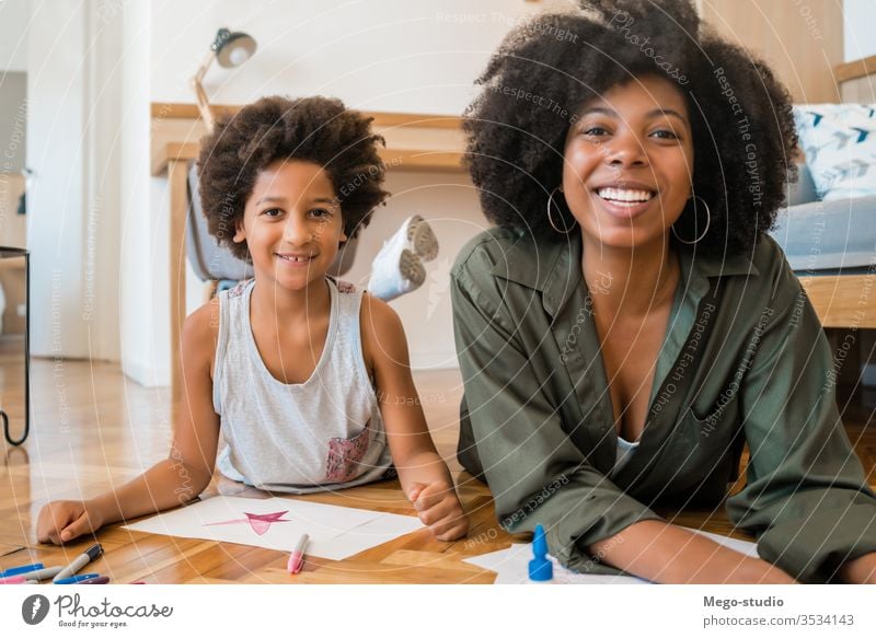 Mother and son drawing with colored pencils on floor. fun mother home together mom black people african american mixed race family kids leisure floor fun indoor