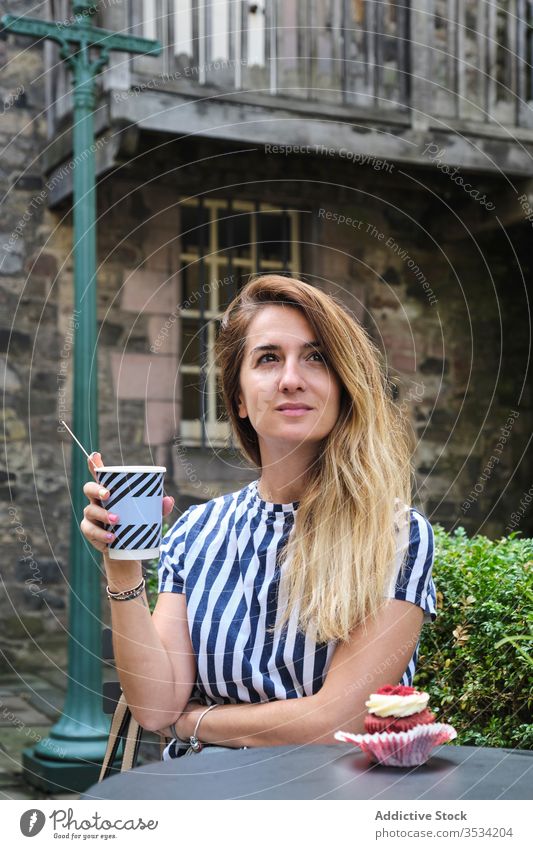 Thoughtful woman with cup of coffee and cupcake in cafe beverage square old town content dream thoughtful dreamy lifestyle free time rest hot drink bake cup