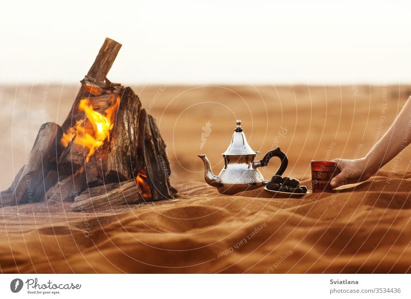 Dates, teapot, cup with tea near the fire in the desert with a beautiful background dates ramadan arabic culture coffee food kettle tradition sand turkish sun