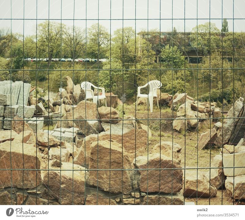 sit in Hoarding Construction site stones havoc Muddled Plastic chairs Opposite two Landscape huts Sky Exterior shot Deserted