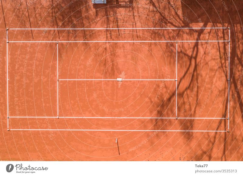 a tennis court from above sport sports tennis courts ash orange white lines sun shadow summer winter sharp tennis net tennis nets ball balls tennis ball trees