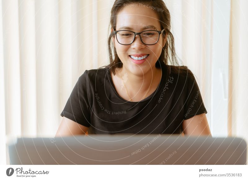 happy woman using laptop. Young Asian woman sitting at home and working on laptop asian attractive candid casual cheerful coffee shop computer conference curly