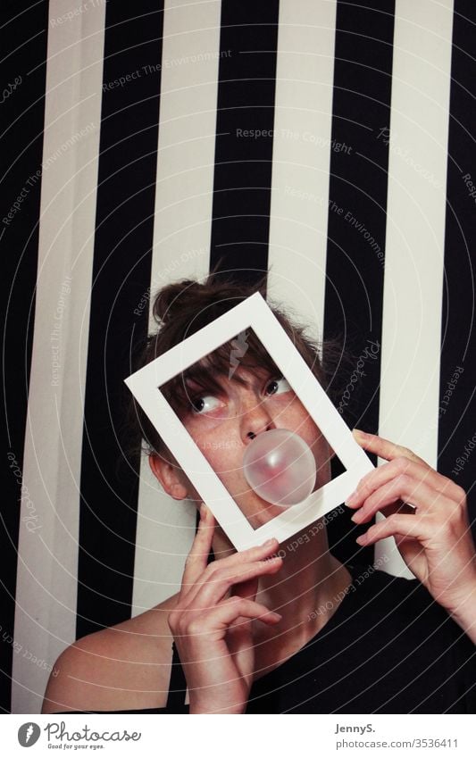 Woman with chewing gum bubble and frame in front of black and white striped background Chewing gum Chewing gum bubble Frame black and white stripes portrait