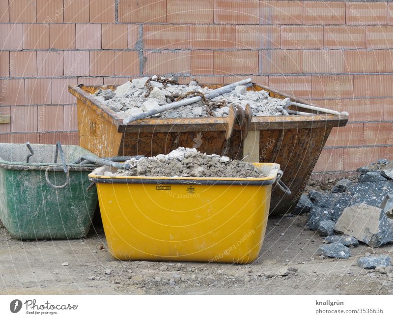 Three differently sized and differently coloured containers with building rubble on one construction site Construction site Building rubble