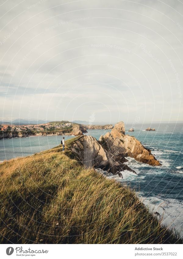 Male traveler standing on rocky seashore in summer in Spain view man photo camera backpack seascape nature trip vacation coast spain rest picturesque landscape