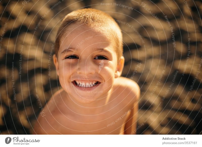 Cheerful boy on beach in evening sea sunset smile resort shirtless summer vacation relax kid lifestyle rest sand cheerful shore joy coast happy glad sundown