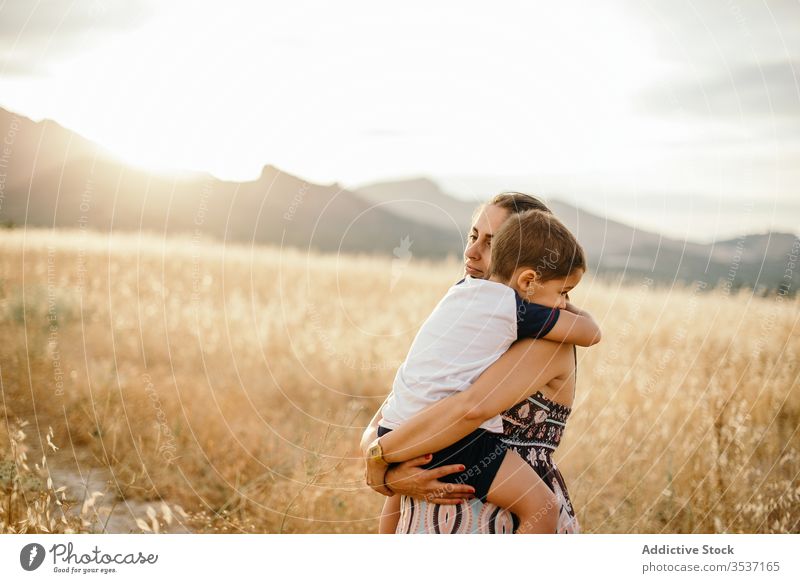 Mother and son resting in field mother sunset hug carry mountain love grass evening woman boy adult meadow sundown sky nature together countryside twilight dusk