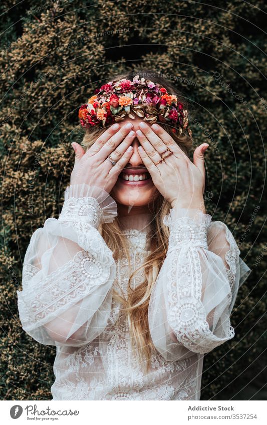 Happy bride covering eyes near bush woman garden smile cover eyes green summer wedding young female bridal dress floral wreath shrub happy cheerful joy flower