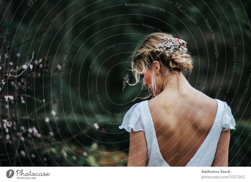 Blond bride resting in yard woman stand wedding dress wreath flower young elegant female translucent floral serene event celebrate sit tranquil calm peaceful