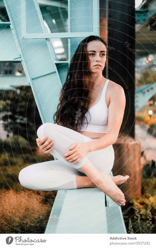 Thoughtful woman sitting on metal beam of bridge cityscape thoughtful sportswear enjoy dreamy balk female pensive contemplate calm serene tranquil relax