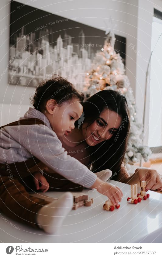 Mother and son playing with wooden toys on table mother home bonding cozy upbringing preschool parent kid cheerful fun woman boy smile game childhood ethnic