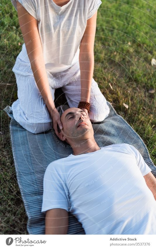 Relaxed couple meditating on green grass yoga meditate lying mat together eyes closed harmony meadow calm pose field spiritual massage white lawn summer tree