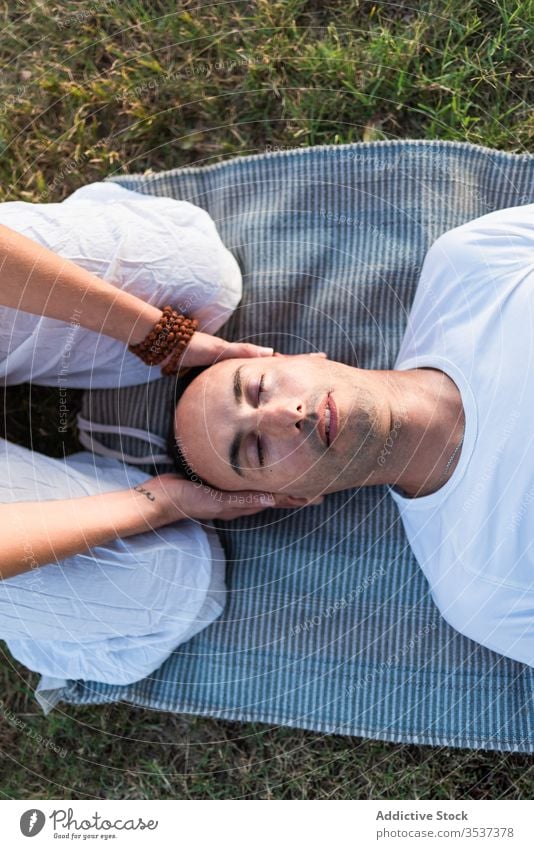 Relaxed couple meditating on green grass yoga meditate lying mat together eyes closed harmony meadow calm pose field spiritual massage white lawn outdoors