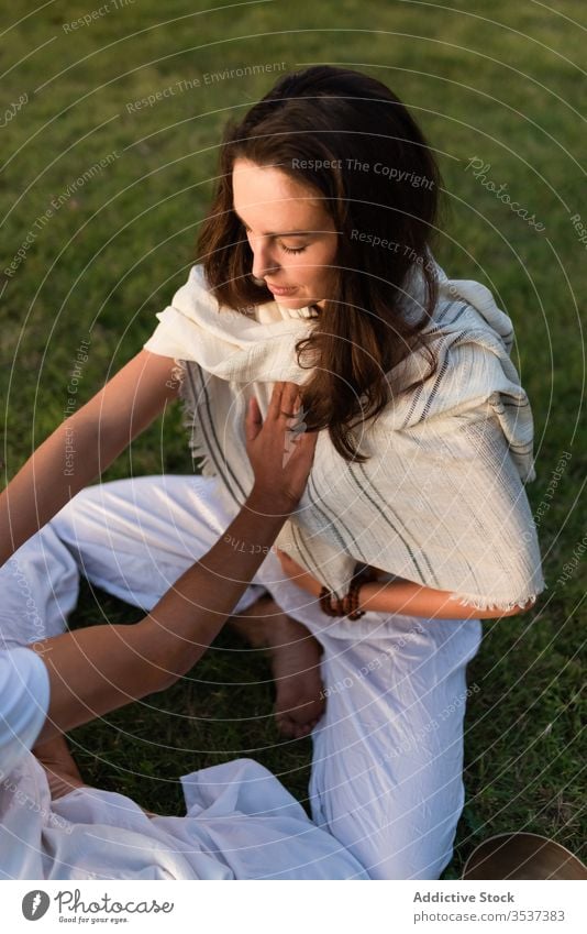 Loving couple doing partner yoga in nature opposite meditate lotus pose calm zen heart lawn eyes closed stomach enjoy green together summer tree park