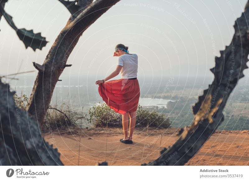 Female hipster at viewpoint on hill woman travel sunset cover face enjoy wanderlust adventure female sigiriya sri lanka casual t shirt skirt stand sand terrain